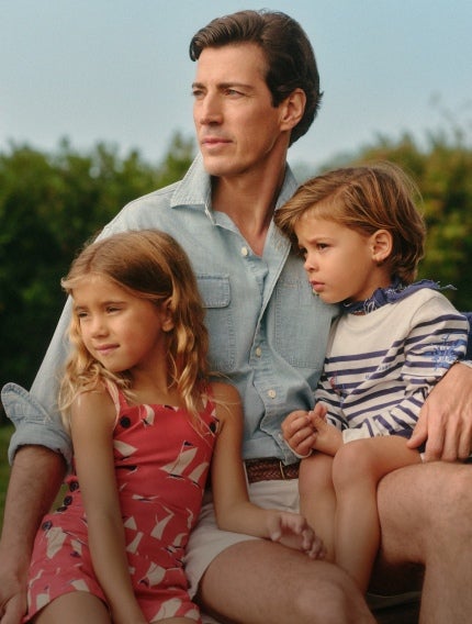 Photograph of dad in chambray button-down with two kids in Polo attire.