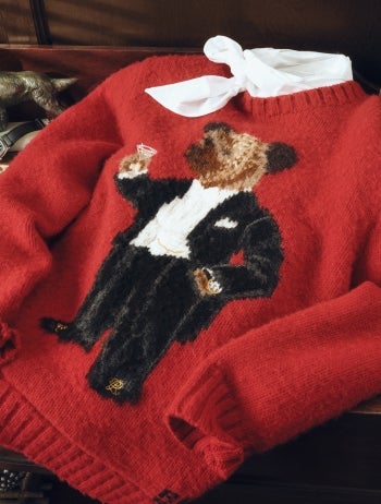 Blue sweater with knit Polo Bear family at front hanging on hanger.